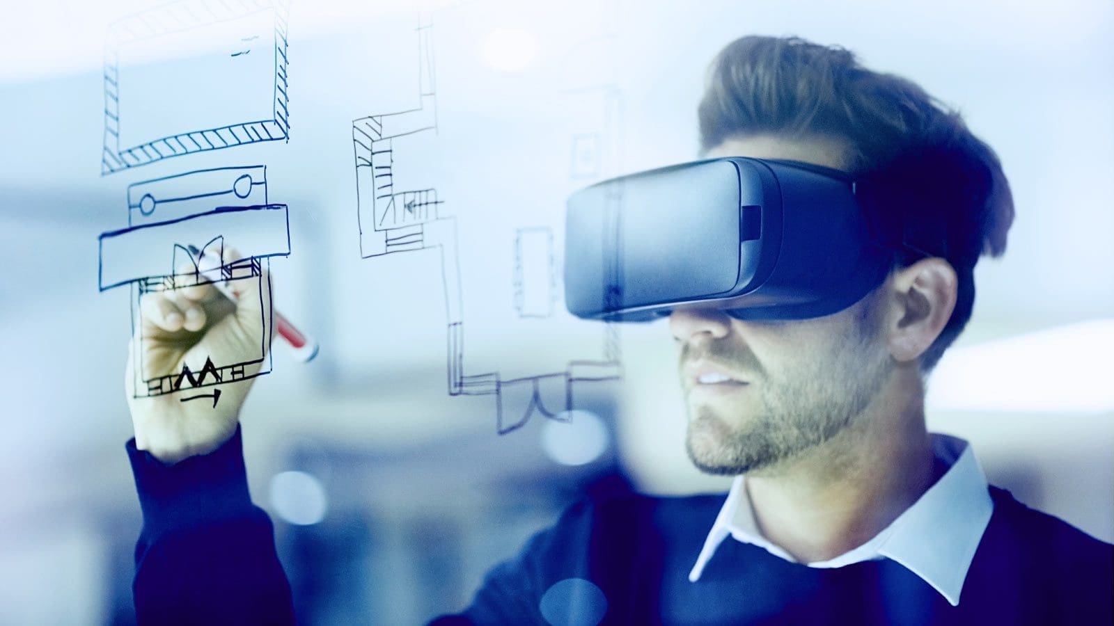 Man wearing VR headset drawing schematics with a marker on a pane of glass
